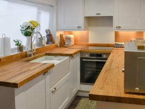 una cucina con mobili bianchi e un lavandino di Beachview Cottage Scratby a Scratby