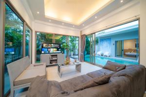 a living room with a large couch and a television at Bang tao modern holiday style pool view high speed WiFi in Laguna Phuket