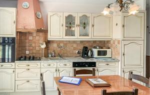 a kitchen with white cabinets and a wooden table at Gorgeous Home In Gueschart With Kitchen in Gueschart