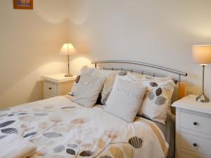a bedroom with a bed with pillows and two lamps at Percy's Place in Alnwick