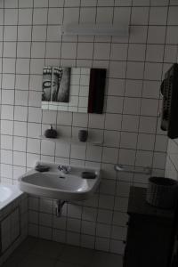 a white bathroom with a sink and a mirror at Gîte les beaux-arts in Ronzon
