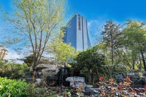 a garden with a tall building in the background at Langfang Arcadia International Hotel in Langfang