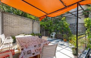 a patio with a table and chairs and an orange umbrella at 4 Bedroom Awesome Apartment In Sveti Juraj in Sveti Juraj