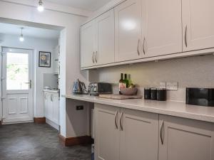 a kitchen with white cabinets and a counter top at Tynedale in Keswick