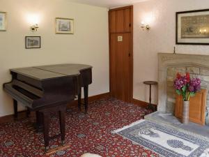 a living room with a piano and a fireplace at Liverton Lodge Farmhouse in Skinningrove