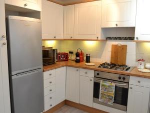 a kitchen with white cabinets and a stove top oven at Roland Cottage in Falmouth