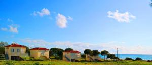 a row of houses on a hill near the ocean at Romanos Beach Villas in Romanu