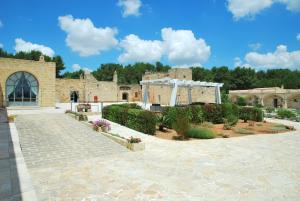 um grande edifício de tijolos com um jardim em frente em Masseria Relais Santa Teresa em Sannicola