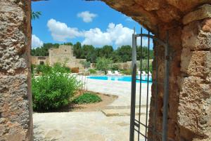 a gate in a stone wall with a swimming pool at Masseria Relais Santa Teresa in Sannicola