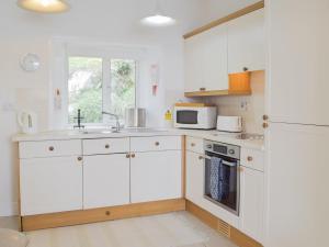 a kitchen with white cabinets and a sink and a window at Cliff Cottage - Uk43207 in Dale