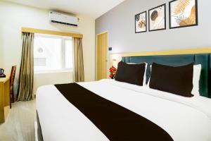 a bedroom with a large white bed with black pillows at Super Townhouse Aarav Business Hotel in Hyderabad