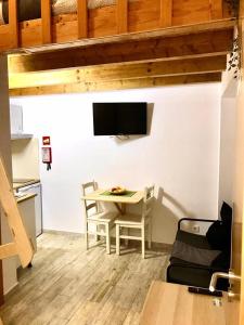a dining room with a table and a tv on a wall at e5túdio frt in Peniche +9 photos