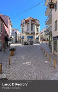 a city street with cars parked on a brick road at e5túdio frt in Peniche