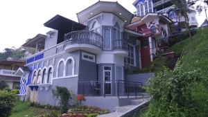 a large white house with a balcony at Villa Dalia Puncak CCC9-26 in Cikujang