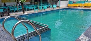 a swimming pool with blue chairs and tables at cbc joy resort in Calangute