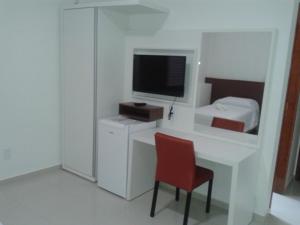 una habitación con un escritorio con televisión y una silla en Hotel Cristal, en Turmalina