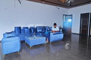 un homme assis sur un canapé bleu dans une pièce dans l'établissement Hotel Shiva Palace, à Khātu 6 autres photos