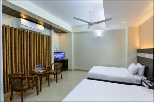 a bedroom with a bed and a table and a television at Hotel Holy Gate in Sylhet