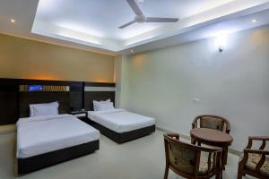 a hotel room with two beds and a table and chairs at Hotel Holy Gate in Sylhet +36 photos