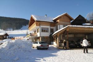 a man standing in front of a house in the snow at Alpenchalet Gosau in Gosau