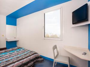Habitación con cama, escritorio y TV. en hotelF1 Saint Brieuc en Tregueux