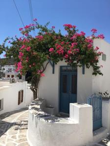 a white building with a blue door and pink flowers at La Maison de Bella in Lefkes