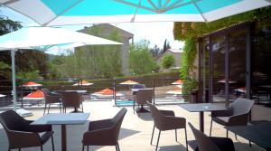 un patio avec des tables, des chaises et des parasols dans l'établissement Lou Paradou, à Gréoux-les-Bains