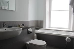 巴茅思的住宿－The Tilman，浴室配有盥洗盆、卫生间和浴缸。