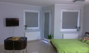 a room with a bed and a table and two windows at Apartament Juventini PT in Puck