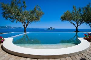 ケリオンにあるKymaros Villasの水辺の景色を望む木々のあるスイミングプールを提供しています。