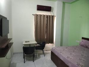 a bedroom with a bed and a desk and a window at Agora Hotel in Muzaffarnagar