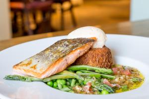 a plate of food with fish and vegetables on a table at The White Hart Hotel in Welwyn