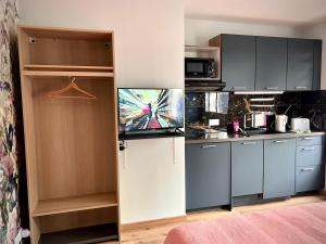 a kitchen with black cabinets and a tv in it at Escale de la râperie logement 1 in Tincourt-Boucly