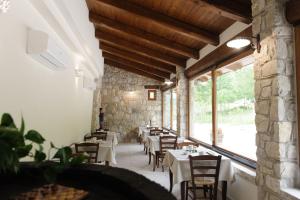 uma sala de jantar com mesas e cadeiras e uma grande janela em Domus Otium em Atena Lucana