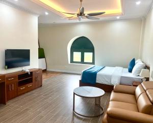 a bedroom with a bed and a couch and a tv at Royal Louis Hotel in Hanoi
