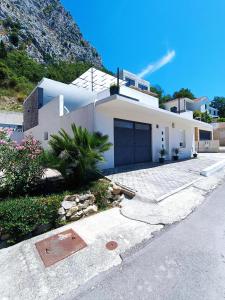 a white house with a mountain in the background at Holiday House "M" Omiš - Newly renovated house with swimming pool, 3 rooms, gym, large terrace with amazing view on town and 6 parkplaces in Omiš