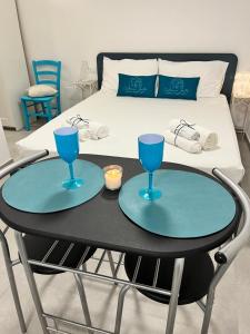 un tavolo con due bicchieri blu sopra accanto a un letto di Cisternone Suites a Formia