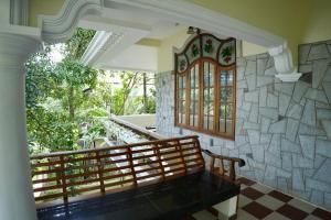 a porch with a bench and a stone wall at Lakshmi Ayurveda & Yoga Apartment in Kovalam