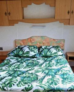 a bed with a green and white comforter at Leśna Aura in Ponizie