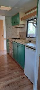 a kitchen with green cabinets and a white refrigerator at Leśna Aura in Ponizie