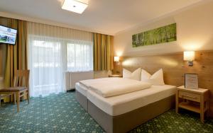 Habitación de hotel con cama y TV en Hotel Garni Birkenhof en Mayrhofen