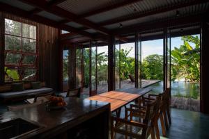 a dining room with a table and chairs and a view of the water at Scarlet Pavilion in Thôn An Vân Thượng