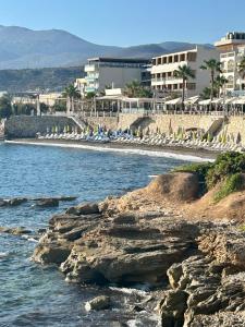 a beach with umbrellas and chairs on the water at Andromeda Apartments & Studios in Hersonissos