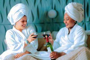 two women in white holding glasses and a bottle of wine at Hotel Miraflores in Ibarra