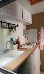 a kitchen counter with a sink and a laptop on it at La Vintage insolite in Lacaze