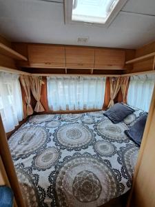 a bed in the back of an rv at Le petit bonheur caravan met voortent en buitenkeuken in Maisonnais-sur-Tardoire