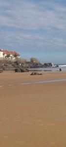 una playa de arena con una casa en el fondo en LA Escollera II Noja, en Noja 1 foto más