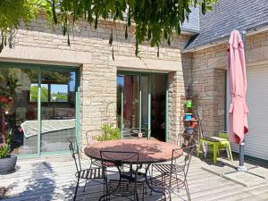 eine Terrasse mit einem Tisch, Stühlen und einem Sonnenschirm in der Unterkunft Maison charmante avec jardin et barbecue à Penmarch in Penmarcʼh