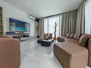 a living room with a couch and a tv at Borneo Bali Villa by Meetstay in Sandakan
