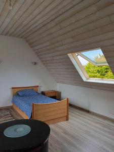 Schlafzimmer im Dachgeschoss mit einem Bett und einem Fenster in der Unterkunft Maison charmante avec jardin et barbecue à Penmarch in Penmarcʼh